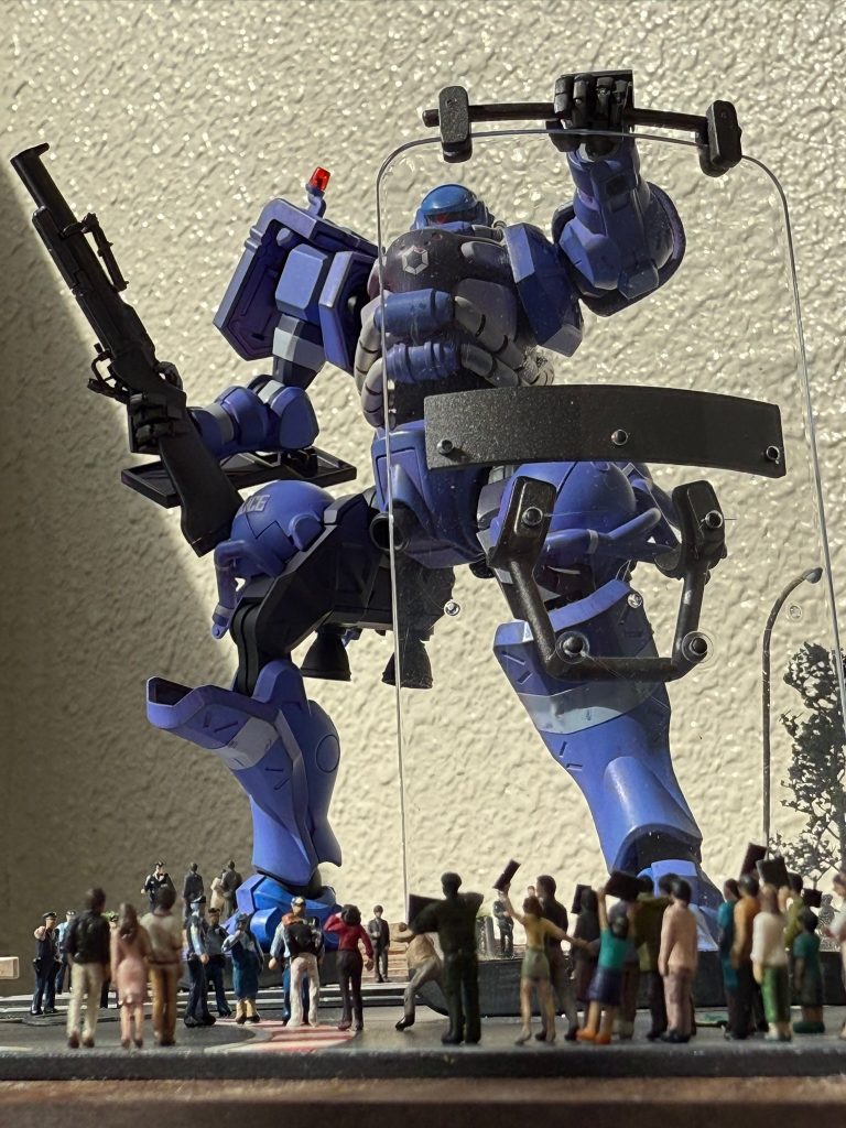 武装はM79 で暴徒鎮圧用に催涙弾を装填。ライオットシールドはコクピットからの視界確保で透明タイプ、バリケート的な運用のため接地用ゴムを装備しています。リトルアーモリーを使いました。