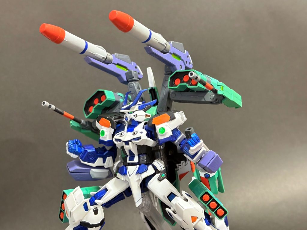 マルチプルランチャーパーツ換装により発射方法を切り替え可能なビームランチャー。シングルバレルとガトリングの二種を主に用い、さらに大型ミサイルの運用も可能。三連ミサイルポッド/固定収束ビームガン脚部と背部に大小一対ずつ備えるミサイルポッド。打ち切った後はパージしデッドウェイト化を防ぐ。/背部の回転式固定ビーム砲。一般的なビームライフルと同程度の火力を有する。三連ガトリング砲腕部に装備する展開式ビームガトリング。追加装甲としての役割も兼ねる。　多分過去一どれがどれか伝わりづらくなってる。一画像に映るものが多すぎます。もちろん増やしたのは私ですがね。この辺はほとんど色塗っただけでほぼ無改造です。　※もちろん核ミサイルではありません。