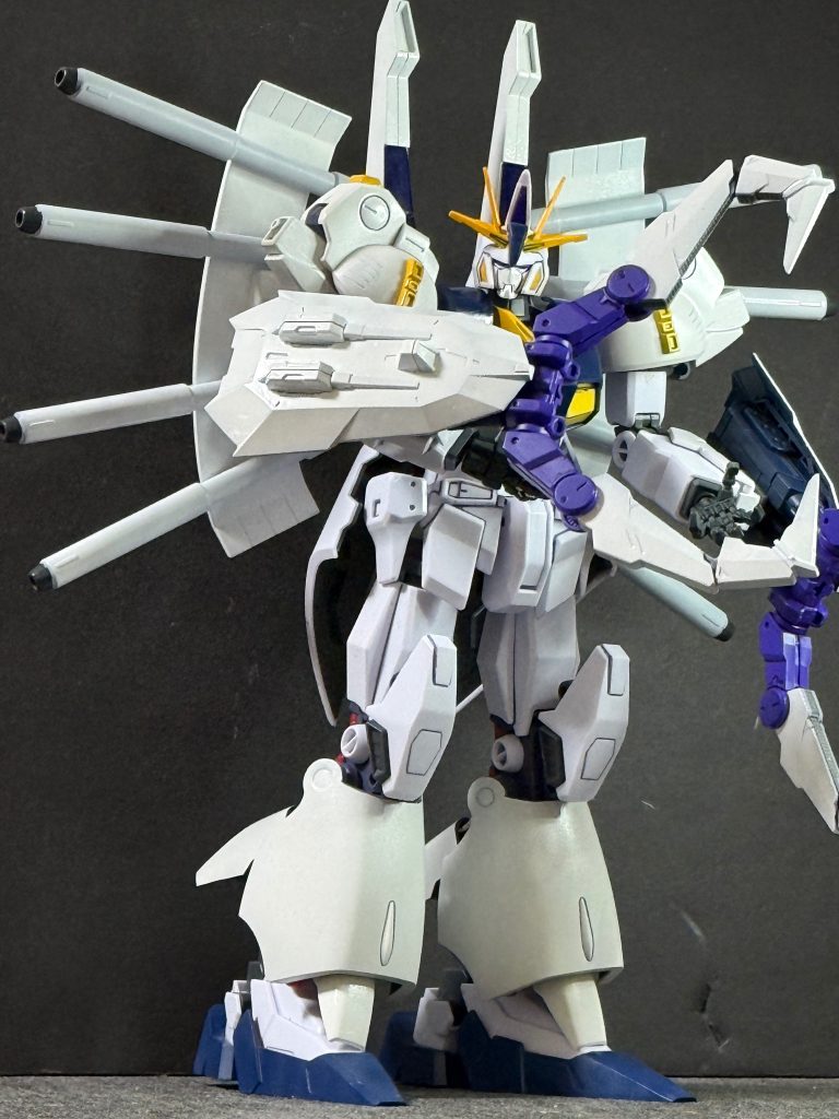 【武装解説④】パラス・アテネ改良型バックウェポンシステムPMX-001 パラス・アテネの重火力思想を継承した背部兵装群。大型バックパックには高出力ビームキャノン、マイクロミサイルポッド、各種エネルギー供給装置を集約しており、遠距離支援から対艦攻撃まで幅広く対応する。従来のパラス・アテネが砲撃戦を主目的としていたのに対し、本機では高機動戦闘中の射撃運用を前提として再設計されているため、機動性を損なうことなく重火力を発揮できる。