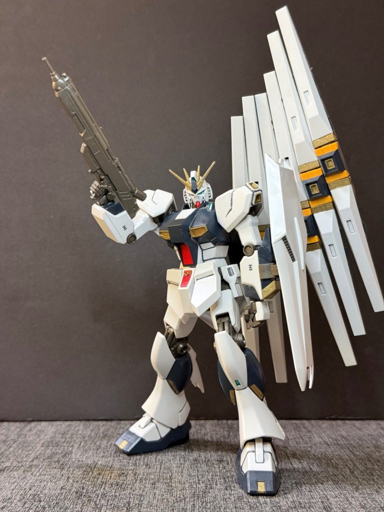 【機体解説】RX-93 νガンダムは、第二次ネオ・ジオン戦争においてアムロ・レイ専用のニュータイプ対応モビルスーツとして計画された機体である。開発はアナハイム・エレクトロニクスが主体となり、ロンド・ベル隊の要求に基づいて実施された。戦局の急速な悪化に対応するため、従来機の技術や設計データを活用しながら開発が進められ、設計開始からわずか約3か月という極めて短期間でロールアウトを達成した。短期間でありながら、ニュータイプ専用機として高い総合性能を実現することを目標として設計された。&nbsp;