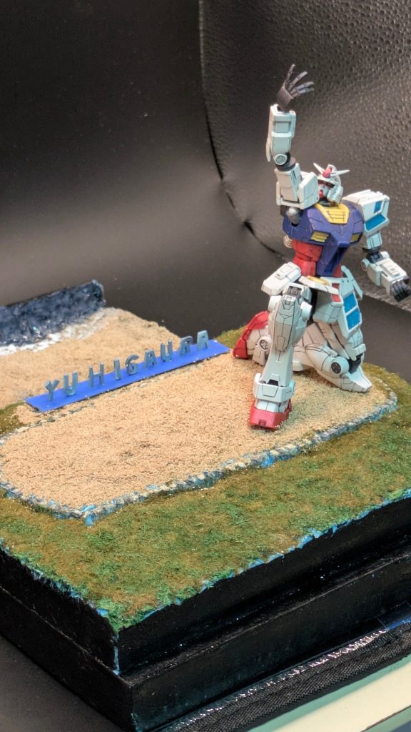 ガンダムは、万博ガンダムの１４４分の1グラスフェザー装備のキットを使用。塗装は、半身に着いているグラスフェザー装備の装甲のクリアパーツの裏をウルトラシルバーで塗装。クリアパーツ表面をルビーレッドで塗装。全モールドにスミ入れした後に、偏光艶消しクリアーでトップコートを吹いて、その上から、ルビーレッドを吹き仕上げてあります。イメージ的には、ガンダムの白装甲部分を丹後の名産品丹後ちりめんに見立てて成形色仕上げで塗りました。