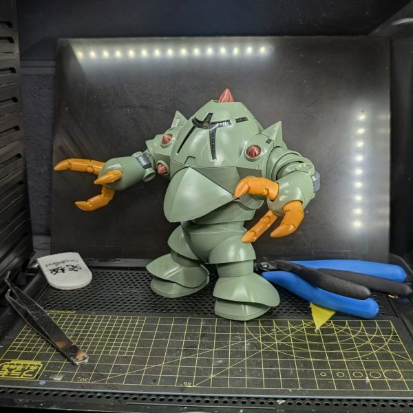 皆様、お疲れ様です。今回は、コツコツ進めていた「HGUC ゾック」の素組みが完了しましたので、その進捗と制作過程での気付きを共有させていただきます。組み上がったゾックを改めて眺めてみると、丸みを帯びたなんとも言えない愛嬌のある可愛らしさと、巨大モビルスーツならではの圧倒的な重量感・格好良さが絶妙なバランスで両立しており、非常に魅力的なフォルムだと感じています。ただ、今回の組み立てプロセスにおいては思わぬところで苦戦を強いられる場面がありました。最も苦労したのが「胴体カバー部分」のはめ合わせです。ゾックはその前後対称という独特の設計上、巨大な外装パーツで内部の構造を覆い隠すように組み上げていくのですが、パーツ同士のはめ込みがシビアで、なかなか上手くはまってくれませんでした。さて、素組みが完了して機体の構造を把握できたところで、次回からはお楽しみの改修作業に入ります。先日組み上げた「リック・ドム」のパーツと今回のゾックを掛け合わせ、お手軽なアプローチではありますが「3脚リックゾック」というオリジナル機体のミキシングに挑戦していく予定です。水陸両用の重装甲と宇宙用の高機動推進器が組み合わさった、異形の3脚シルエットを目指します。どのようなバランスで脚部を接続していくか試行錯誤が続きますが、今後の制作過程も随時アップしていきますので、ぜひ皆様からのアドバイスやご感想をいただけると大変心強いです。引き続き、よろしくお願いいたします!(3枚目)
