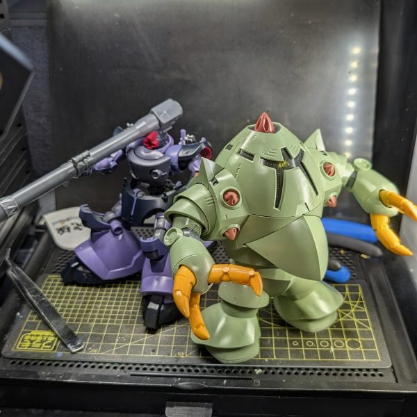 皆様、お疲れ様です。今回は、コツコツ進めていた「HGUC ゾック」の素組みが完了しましたので、その進捗と制作過程での気付きを共有させていただきます。組み上がったゾックを改めて眺めてみると、丸みを帯びたなんとも言えない愛嬌のある可愛らしさと、巨大モビルスーツならではの圧倒的な重量感・格好良さが絶妙なバランスで両立しており、非常に魅力的なフォルムだと感じています。ただ、今回の組み立てプロセスにおいては思わぬところで苦戦を強いられる場面がありました。最も苦労したのが「胴体カバー部分」のはめ合わせです。ゾックはその前後対称という独特の設計上、巨大な外装パーツで内部の構造を覆い隠すように組み上げていくのですが、パーツ同士のはめ込みがシビアで、なかなか上手くはまってくれませんでした。さて、素組みが完了して機体の構造を把握できたところで、次回からはお楽しみの改修作業に入ります。先日組み上げた「リック・ドム」のパーツと今回のゾックを掛け合わせ、お手軽なアプローチではありますが「3脚リックゾック」というオリジナル機体のミキシングに挑戦していく予定です。水陸両用の重装甲と宇宙用の高機動推進器が組み合わさった、異形の3脚シルエットを目指します。どのようなバランスで脚部を接続していくか試行錯誤が続きますが、今後の制作過程も随時アップしていきますので、ぜひ皆様からのアドバイスやご感想をいただけると大変心強いです。引き続き、よろしくお願いいたします!(2枚目)