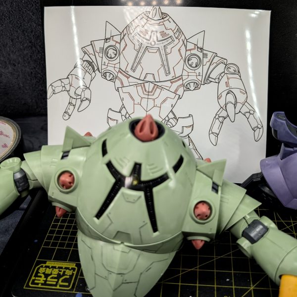 HG リック・ドム(GQ)のパーツと、旧キットの特異なフォルムを持つゾックを組み合わせた、異色のミキシングビルドに挑戦しています。本日は「スジ彫りの下書き作業」にひたすら没頭しました。【本日のこだわりと苦労した点:AI図案の活用】ゾックのようなどこまでも続く曲面装甲に、一からスジ彫りのデザインを考えるのは非常に骨が折れます。そこで今回は、AI(Gemini)を活用してパネルラインの図案を下書き出力してみました。ここで一つ工夫したのが、生成した画像を「コンビニのマルチコピー機で『写真』として印刷する」という手法です。普通のコピー用紙と違い、写真用紙は表面に光沢がありコントラストが強いため、複雑な線画のディテールが圧倒的に見やすくなりました。手元に置いて作業する際の視認性が格段に上がり、非常に役に立っています。【使用ツール:アナログの強み】実際のプラスチック表面への描き込みには、専用のマーカーなどではなく「シャーペンと消しゴム」を使用しています。プラモ初心者の方にもおすすめなのですが、シャーペンなら失敗してもすぐに消しゴムでリセットできるため、図面を見比べながら「ここはもう少し線を足そう」「このラインはくどいな」と、心ゆくまでトライ&エラーを繰り返すことができます。最新のAIテクノロジーでデザインを作り、最後はシャーペンという身近なアナログツールで現物に落とし込む。このギャップと試行錯誤こそが、プラモデル作りの純粋な楽しさだと実感する朝活タイムでした。引き続き、完成に向けてコツコツ進めていきます!(2枚目)