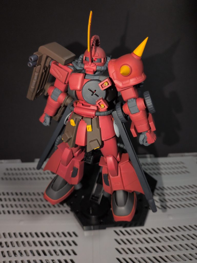 元キットはHGのジョニー・ライデン専用高機動型ザク。腰のビッグガンや左腕の三連ミサイルポッド、左腕の三連マシンガンに頭部のヒートホーク・シンボルや胸部二連バルカンなど、追加装備のほとんどはスクラッチです。ドラムマガジン、給弾ベルト、マガジン類は流用品ですが、マガジンカバーや肩、腰、胸の増加装甲などもプラ材とパテで作りました。唯一、右肩の二連高速破砕砲はキットのシールドを改造したもので、表裏を合わせる際半分だけ差し込み。出来た隙間をヤスリで大きくし、自作マガジンを差し込んでいます。