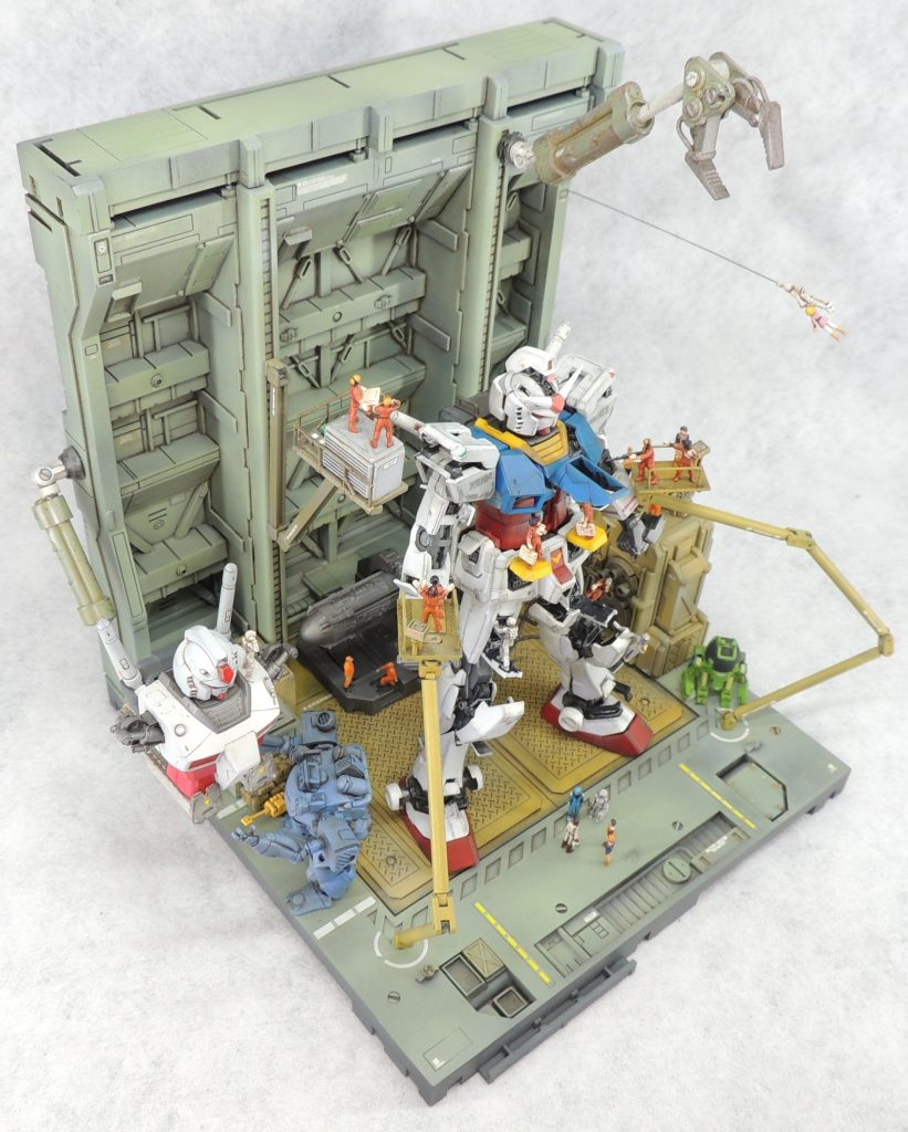 ベースやアームは市販品を使用しました。フレキシブルに可動する高所作業台は、プラ棒や市販のディティールアップパーツ等から自作しています。フィギュアは主にビルダーズパーツの改造ですが、ガンダム背面にある装置やマグネットコーティング車の上にいるクルーは箱庭技研の整備員クルーのガチャ商品を彩色しています。