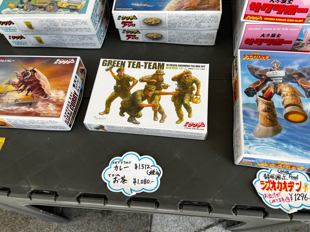 店頭に並ぶ静岡土産。中央は「GREEN TEA-TEAM」…中身は静岡茶🍵。箱絵は先の島村英二氏による物。田宮模型は関係してません。左は駿河湾の深海に生息するオオグソクムシカレー🍛。右は静岡おでん🍢。だそうです。