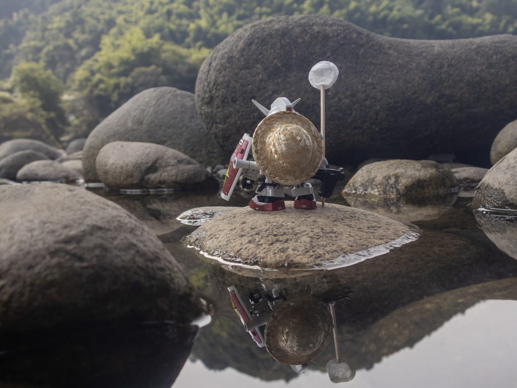 濡れた岩肌の生々しい質感と、水面に逆さに映り込むシールドや麦わら帽子のディテール、そして霧吹きの水滴が太陽光をキュッと集めて作る無数のハイライトが奇跡的に噛み合って、ノスタルジックで重厚な1枚が撮れました。