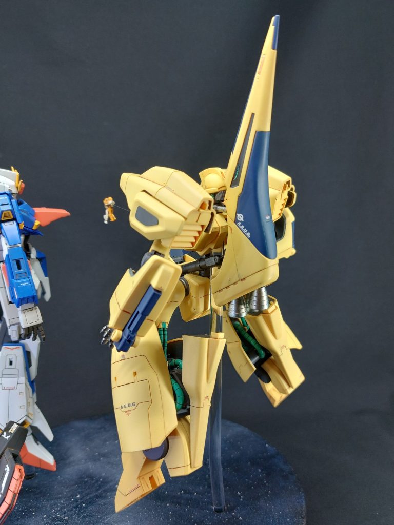 ■メタスについて(2/3)メタスは変形機構を温存したかったので、敢えて大規模な改修は行わず、スジ彫りやマーキング等によるディティールの追加に専念しています。両肩の丸い緑色の上のひさし部分を、アニメのイメージに基づいてカットしました。HG初期のキットなので、主要パーツのほとんどに合わせ目が真ん中にきたり、ポリキャップが露出したままになっていたり、と何かと気になるところばかりですが、根気強く処理しています。全身にスジ彫りやモールドを追加するとともに、緑色のセンサー部分にはUVレジンを用い、クリアパーツのような質感にしています。