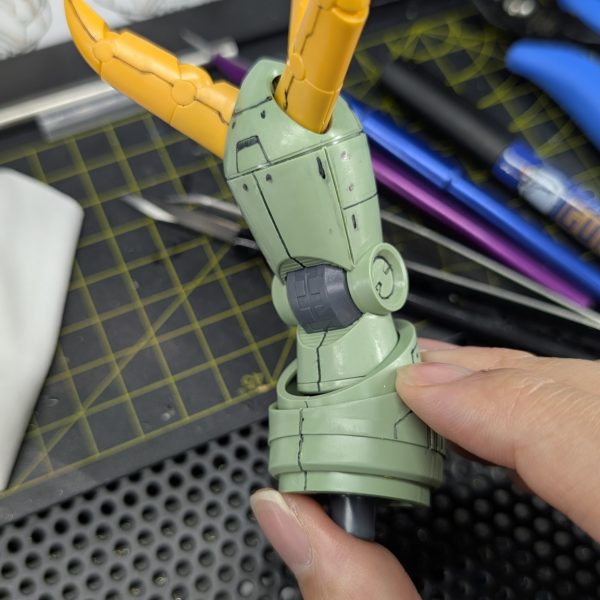 継続朝活62日目、「リック・ゾック(仮)」の右腕部スジボリ作業がついに完了しました!今回は曲面の多い球体関節へのライン彫りということで、ツール選びにこだわりました。ガイドには曲面への追従性と耐溶剤性が抜群な「ニチバン クリアラインテープ」を使用。まずはケガキ針とキサゲで力を入れずに丁寧にアタリをつけ、本彫りには「ラインスクライバーCS 0.15mm」を投入しました。このスクライバーは刃のビビリが起きにくく、底面がフラットに仕上がるので本当に頼りになります。「溝の深さが均一になっているか」という点は、目視だけでは分かりにくいため、今回はガンダムマーカーのスミ入れペンを実際に流し込み、塗料の保持力を見ることで深さが十分に足りているかを確認する工程を挟んでいます。(比較画像右側のAfterが、実際にスミ入れをして確認した後の状態です!)リック・ゾック特有の「両腕が右手」という異質な構造に向き合うのは大変ですが、完成した時の圧倒的な情報量を想像するとモチベーションが上がります。明日からはついに脚部の作業へ移行します。完成までの道のりはまだまだ長いですが、この調子で毎朝一歩ずつ進めていきます!(2枚目)