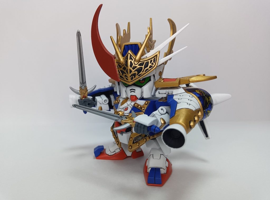 双龍刀この機体はガンダム野郎終盤に登場する読者公募の改造戦士で、白龍頑駄無、青龍頑駄無、赤龍頑駄無が合体した三龍頑駄無となるところ、三流と響きが同じで弱そうなため太陽と書いてサンと読ませるSD戦国伝らしく命名されたそうです。