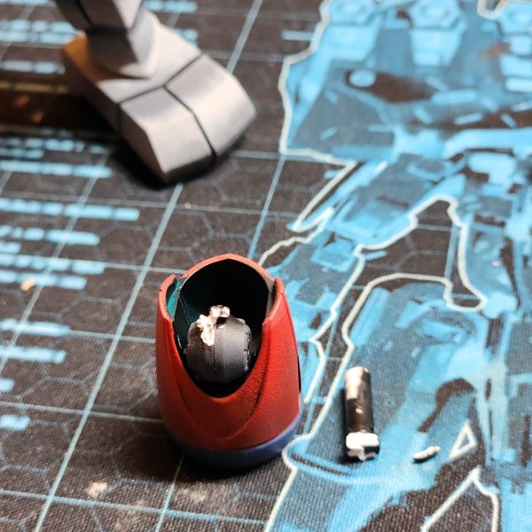 色を選び、パーツを塗装し、いざ組み立てようとしたその時……しまった、やらかしてしまいました。プライマーの吹き付けが不十分で、下地の緑色が残ってしまっている箇所がいくつかあったのです。隠れるだろうと思っていた場所が、組み立ててみると緑色が見えてしまっていました。また、ひと塗りでしっかり発色する「オペーク(不透明)」タイプの塗料も試していました。素早く塗装したり下地を作ったりするには最適ですが、グラデーション表現にはあまり向いていませんね。扱いが難しい塗料です。そして、何よりも痛恨のミスをしてしまいました。肘の関節を折ってしまったのです。接続用のピンや軸にまでプライマーを吹いてしまったせいで、パーツをはめ込むのが非常にきつくなっていました。無理に力を入れた結果、ポキリと折れてしまったのです。本当にショックな瞬間でした。二度と同じ過ちは繰り返しません。今後はピンの部分をしっかりマスキングするようにします。Colours selected, panels painted, parts connected, hang on a second... oh no. I messed up. There was a couple of parts I didn't spray primer thoroughly enough and left some green on show. I thought that these areas would be covered but when I've come to assemble, some green can still be seen. I've also been trying out these 'OPAQUE' colours which allow for instant coverage. They are great for quickly coating and applying a base but not so much for gradients. Very tricky. And now, the biggest mistake of them all. I broke the elbow joint. Because I have sprayed primer over the pegs and shafts they became super difficult to insert. I applied too much pressure and broke it. It was a devastating moment. I won't make this mistake again. I should mask the pegs hence forth.(5枚目)