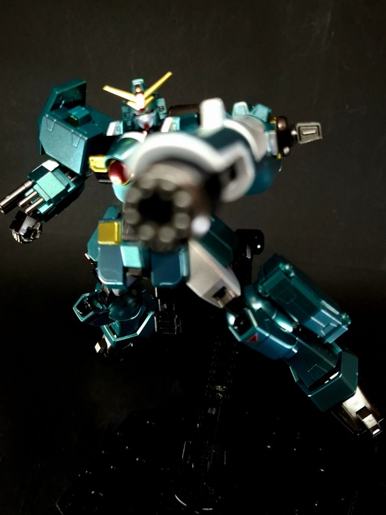 武装編集インナーアームガトリング[5]バックパックの左側に連結された大型ビームガトリング砲[2]。使用時は左腕をほぼ丸ごと格納するかたちで合体し、高い威力と速射性を発揮する[1]。左腕の動力を利用するため、機体の機動性は低下しない[1]。高速で発射されるビーム弾は重装甲をも容易に貫通する威力を発揮し、この武装のみで通常のMS1機分の総火力を軽く超える。劇中では砲身ユニットの頑強さを活かし、盾代わりに敵弾を防御する使用場面が描かれている。