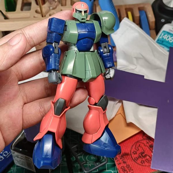 HGニューレッドザクの脚部と頭部を使用し、ニューレッドザクの頭部をオリジナルの口部と組み合わせることで、全体の形状を維持しながら頭部を小型化しています。手部はバンダイの丸型ハンドに交換し、下腿部の外装装甲を延長しています。（2枚目）