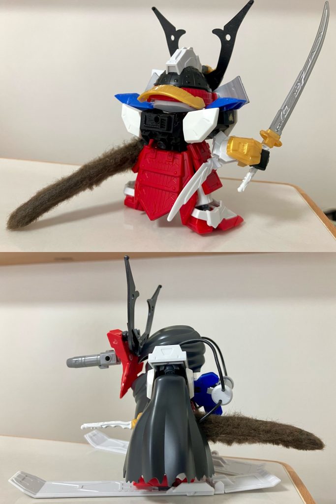 SDWヒーローズ輝羅鋼物語・78代目武者頑駄無をベースに、ジャンク品で入手した旧キット版ガンダムF90から特徴的な意匠を取り入れて作りました。小柄で俊敏なイメージのある義経と機動性能の高い小型MSのF90の設定を重ね合わせ、78武者本来のゴテゴテ感を減らし、素体武将のデザインはシンプルな軽量化の方針としています。Cタイプ装備はスキー板・背部肩部のパーツをMG 1/100キットから取り入れ、白マント部分はSDWヒーローズ・レイフガンダムGP04のパーツを使用しました。