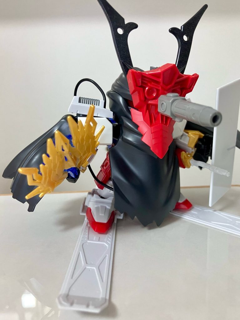 寒冷地仕様のCタイプ装備をSD武将ガンプラ化するのは、モチーフ人物の選定も含めて悩ましい部分が多かったのですが、雪山の鞍馬寺で修行時代を過ごした義経という題材を取る事で、アレンジは強めですがCタイプ装備を何とかキャラクター性に落とし込めたかなと思います。鞍馬天狗の面はSD戦国アストレイの鬼面パーツをアレンジして装着し、天狗の羽団扇っぽい武器を持たせるなど工夫しました。通常形態でも平安武者が用いた獣毛皮製をイメージした鞘や義経に所縁の名刀をモチーフとした武装、板の盾にF90のシールドのデザインを見立てる等、楽しく義経モチーフのSD武将化が出来たと思います。また今回SDガンプラ企画での源義経という事で、同主催者様の過去の #歴代武者頑駄無揃い踏み企画 という別企画で参戦させて頂いた33代目武者頑駄無・平清盛頑駄無との関係性も設定に盛り込みました。