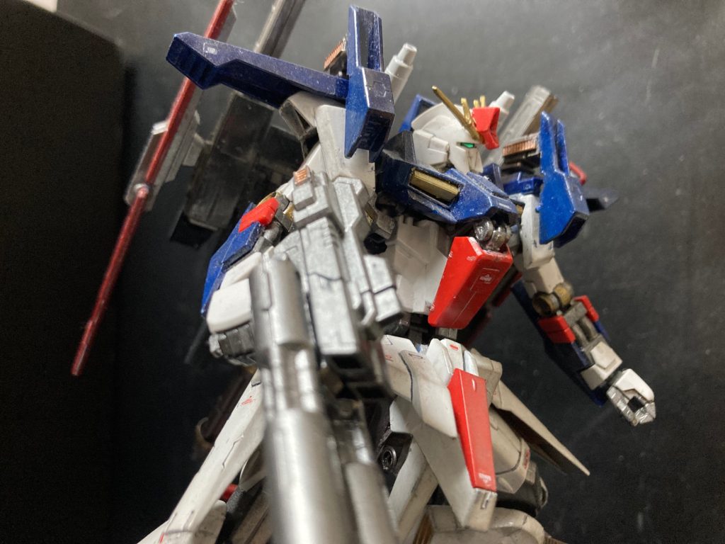 機体解説 :　ZZ REVIVEZZガンダムで恐竜型進化を遂げた可変MSだったが、合体変形による扱いづらさ、メンテナンス性の低下、コスト高などの問題があった。第一次ネオジオン抗争の最終決戦に至っては、可変というメリットと無くして強化型ZZガンダムとして火力と堅固性を重視された。その為、次世代可変MSを開発するにあたり、基本に立ち返り、単機での機動力と高いメンテナンス性を重視されるに至った。本機はZZガンダムの単機での大火力と上の課題を重視して設計されたMSである。