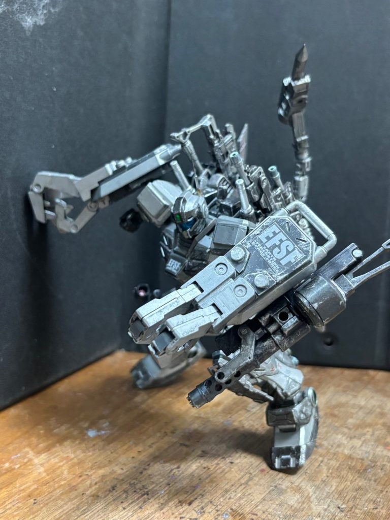 【武装紹介（WEAPON SYSTEMS）】1. 両腕部グラップシールド増加装甲技術を発展させ、左右の両腕にそれぞれダイレクトにマウントされた2枚の特殊シールド。激しい正面砲火を左右から完全にシャットアウトする鉄壁の防壁であると同時に、シールド自体が可動し、直接敵MSを挟み込み、文字通り『圧壊・握り潰す』ための巨大な万力（グラップ・クロー）として機能する。大型スラスターが生み出す凄まじい推進力をそのままシールドに載せて敵に突撃し、クローで標的をがっちりとホールド。そのまま機体出力と超怪力によって敵のフレームやコックピットを左右からベキベキに挟み潰し、ゼロ距離で完全圧殺する恐怖の質量兵器である。