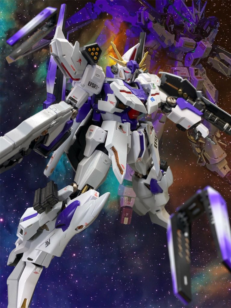 またソフトウェア面でも本機からの新たな取り組みとして、パイロット補助と、半自立行動を目的とした擬似人格型コンピュータの搭載が開始された。これは、個々の試作機から前線の配備機に至るまで、ネットワークに接続するありとあらゆる機体が実験やテストを繰り返すことで膨大な数のフィードバックを得た本体が自己成長。数年かけて、歴戦のNTパイロット並みの戦闘用AIを育成してゆく長期プロジェクトの足掛かりとなる。&nbsp;「アルゴス。なるほど、百の眼を持つ死角のない巨人と言うわけか。」&nbsp;「大佐、ホメロスはご存知ですか？」「ん？あぁ、たしか古代の詩人だったか？」&nbsp;「彼によれば、アルゴスとはオデュセウスの帰りを待ち続けた忠犬の名であったとされています。あのオデュセウスですら故郷への帰還には20年かかったのです。もう12年。でも、まだ12年……我々がまだ英雄の帰りを待ち続ける忠犬をやっていても、いいじゃありませんか──」その研究員は、英雄の帰還を待ち望む…というよりは、何処か戦友の帰りを待ち続けている…そんな表情をして、宙を見つめていた。