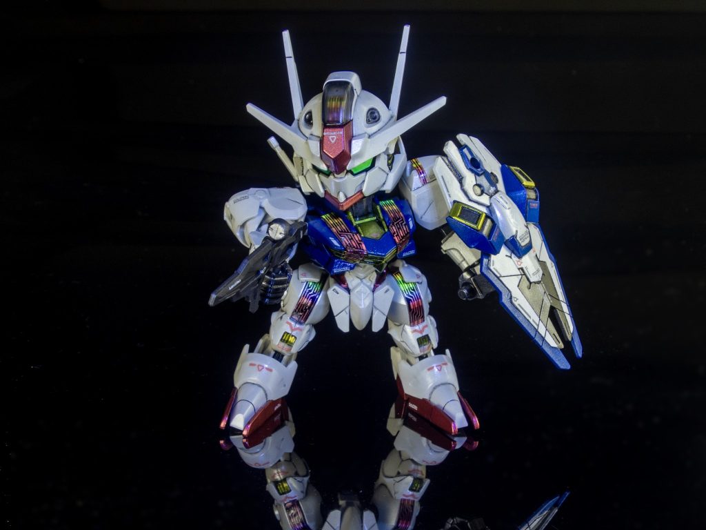 仕上げ ＆ デカール今回、FM版のエアリエルに附属シールを元に、自作のデカールも用意していましたが、今回はあえて自作を温存し、「ガンダムデカールNo.133（水星の魔女汎用1）」のデカールを使用しました。スミ入れを完全に終わらせた後にOHPフィルムを強力圧着し、最後にパーツ全体へ最終トップコート（GX112）を肉厚にしっとり吹き付けました。クリア樹脂が100μmのフィルムのフチの段差（切断面）を滑らかに埋め尽くしたため、乾燥後に磨き上げることで段差が完全に消滅し、装甲そのものがデジタルパネル化したようなフラット鏡面へと覚醒しました。