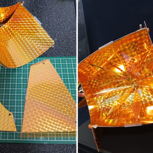 ①透明プラ板でカードベースを作成。背面はC字に曲げ、そこに側面を3ミリ軸で接続。UVレジンで複製して作ったちくわ状の３ミリ接続パーツをつけて隙間なく固定する形。やや斜めに傾いて採光できるようにしつつ、キャラを空間として包めるような形に。②ホロ部分はダイソーのホログラムデザインペーパーをテープで付けただけ。適当に何枚か買ってきたものだけど、最近仕様変更したのか輝き方が良いものと鈍いものがあるので、より輝いてる方を使用。額縁となるカードフレーム部分は同じく100均の連結ディスプレイベースの端を切り取ったもの。ネームプレートと太陽マークの土台部分は３０ｍｍのティルトローターのパーツ。ゴッドガンダムの名前部分はＲＧシャイニングに付属のランナーから。カードフレームは当時もちょっとダサさを感じてたので、ついでに立体物として奥行きを見せられるような形に少しだけアレンジ。③透明プラ板はクリアオレンジで塗装。回転させて横の側壁が見えてもなるべくキラキラ空間が繋がって見えるように。側壁の外側に直接オレンジホロペーパーを貼るよりかはこちらの方が自然に見えたので。④カードフレームの太陽マーク部分は、100均の☆マークの型からUVレジンで作成。中には銀のホロペーパーを下地に透明ホロペーパーも少し入れた。☆部分の真ん中だけ丸くへこんだ造形になってるので、ホロの輝きだけでなく物理的な屈曲によっても表情が出せるように（写真だとほぼわからないが）。中心の☆は３ミリ軸接続、他の小さな部分はUVレジンの硬化で接着。硬化後のポロリが恐いのでUVレジンでの接着は少しはみ出すくらい塗ったが、見映えなど良くなるようにここはもっといい方法を考えていきたいところ。他の文字や数字も100均のレジンの型から作った。　背面の集中線のような演出パーツも作成。ダイソーのラッピングタイにUVレジンを薄く塗って輝かせつつ形を固定、数本を中心で束ねてネオジム磁石も添えてレジンで接着。このラッピングタイは空間に線のようなラインを入れるのに重宝しそう。　カードベース側にはマグネットシートをテープでくっ付けるだけ。後ろは見えないので適当。カードベースは底面と後ろも横にランナーを通して３ミリ穴パーツでさらに固定、中央と側壁の隙間をなくしていく。⑤物理的なキラホロエフェクトも製作。クリアオレンジで塗った透明プラ板に透明ホロシールを貼ってUVレジンを塗る。やや水っぽい質感になってしまうが、ちゃんと光を反射して存在感を持って欲しかったのでレジンは厚めに塗った。⑥右の側壁は縦に長いものも用意して、パース付きカードダスにもなるように。これでカードベース部分の工作はおしまい。（6枚目）