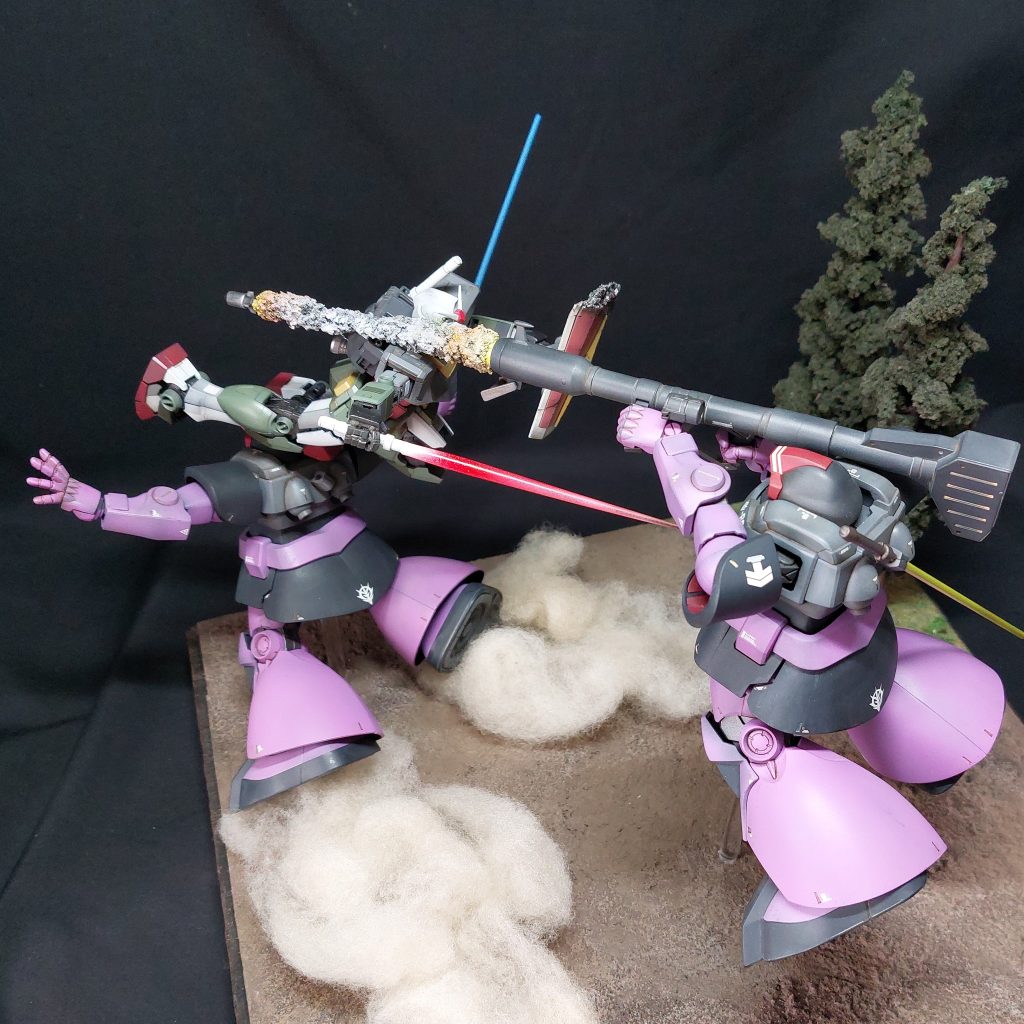 ■最も重要なマッシュ機について3機のドムのうち最も改造したのはマッシュ機で、ジャイアント・バズーカを正面に構えさせる改造をしました。まず、肩口やヒジを切り欠いて可動範囲を広げました。次に、HG1/144リバイブ版ギャンのように、両手首を曲げた状態で固定しています。手首の隙間は、プラ材や市販のディティールアップ用パーツで埋めました。右手は胴体に引き付けて手首が顔の近くにくるようにし、左手は伸ばした状態でグリップを掴むように調整。マッシュ機がジャイアント・バズーカを正面に向けて構えることができるかどうかが、このジオラマの成否のカギだと考え、ガンダムとの間合いも含めてバランスを試行錯誤しました。