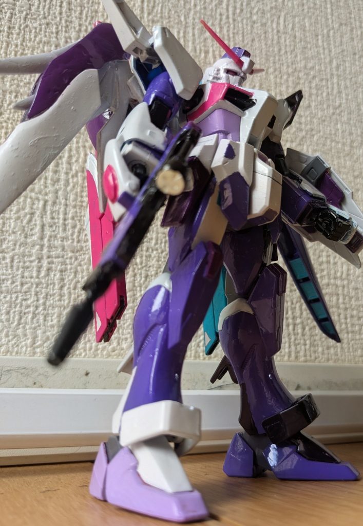 逆サイドからあおりで１枚。&nbsp;色レシピは次の通り。白:ガンダムホワイト（胴体、肩、腕装甲、膝まわり）紫:パープル（上腕、下腕内側、腰、脚、左翼、トサカ、ライフル）薄紫:MSパープル（くちばし、胴回り、右スリッパ、ポイント色々）緑:あさぎ色（ビーム砲、シールドポイント）ピンク:ルブリスピンク（対艦刀、アンテナ、胸周り手甲ポイント、シールド中央）黒:ブラックナイトスコードブラック（胸、手、関節）紫がかった白:（MSパープルに白。頭、右翼、右ブーメラン、右下腕、右サイドスカート上部、右脚ポイント、シールド周り）赤紫:紫にマゼンタ（翼上部、ウエポンラック、サイドスカート下部、膝、シールド）赤っぽい黒:スコードブラックにマゼンタ（左ブーメラン、左サイドスカート上部、左脚ポイント）濃いピンク:メタリックピンク（マーカー塗装。カメラ関係）&nbsp;紫がかった白と赤っぽい黒、リアルに見るとまぁまぁ分かるんですけど、写真だと分からないですね（笑）