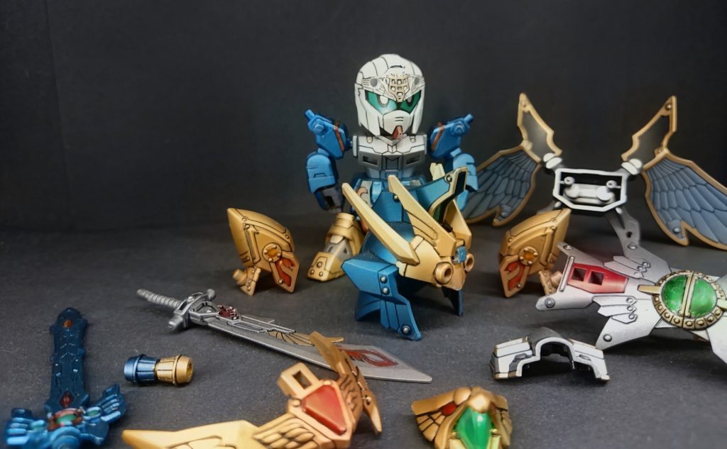 カラーレシピホワイト…パールホワイト(T)ボディ黒…ライトガンメタリック(T)ブルー…コスモメタブルー(GM)レッド…ロイヤルメタレッド(GM)ゴールド…レッドゴールド(GM)グリーン…メタリックイエローグリーン(GM)後、蛍光クリアイエローグリーン(G)羽全体…メタリックブラック(T)羽部分…スカイブルーアルマイト(T)仕上げ…水性プレミアムトップコートつや消し(C)(T)タミヤ・(C)クレオス・(G)ガイアノーツ・(GM)ガンダムマーカー以上でスプレー、筆塗りで塗装しております。感想まとめ…この頃はエアブラシを購入してましたが、清掃が億劫でガンダムマーカーエアブラシで製作する事がメイン塗装になってました。まだラッカーや水性の違いに気づいて居ない塗り方をしてますね、ガンマカの後にガイアのラッカー塗ってます💦キット自体は三国伝の中でも出来の良いキットだと思いました、バランスも良いしギミックも、そこそこあります。余剰パーツを背中に収納出来る所もボクは嬉しいです。第24話『｢伏龍｣諸葛孔明！再臨！』(天翔竜孔明νガンダム)へ続く最後までご覧頂きありがとうございます。