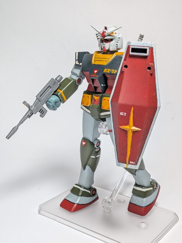 まずガンダムの全身像から。マーキングは哀戦士のドムと対峙しているポスターを見つつ、寂しいところや、ポスターでは見えないところを様々なキットや作例を参考に補完しています。本体は基本工作を行いつつ、いわゆるハの字立ちができるように改造。また盾を拳で握って前に突き出す持ち方ができるように渋みを調節しました。&nbsp;