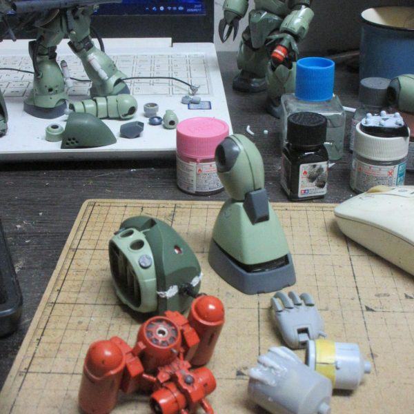 ハイゴッグを念頭に、手長短足ゴッグを作りたいのです。クリアランスを調整しながら股関節を上にしたり、ズゴックのパーツを流用したりして調整してますが、どこからともなくボスボロット臭が漂ってきました……脛の形状と独特足首表現からして、脛部分をぶった切って縮める加工は無理っぽいですよね。頭のすげ替え、かなり一致しますが、さすがにポン付とはいかずに柱の延長とか厳しい加工をしていきます。シャア専用ゲルググをミキシングコンテストに出すために、こちらは一時中断してましたが、再開して、ハイゴッグらしい腕カバーとかバックパックとかやってます。（5枚目）