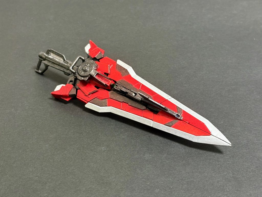 タクティカルアームズマレウス　プロトアストレイシリーズ向けに作られた可変武装、「タクティカルアームズ」をベースに、ケルメシヌスフレーム用にマイナーチェンジを施したもの。原型と同じく変形することで多彩な戦術を展開可能なマルチツールとなっている。　デカくて殴れそうなので“鉄槌”の名前をつけてます。改造点としては、刃先を延長したり、根本を細くしたり、スラスターの角度を変えたり、パーツ追加したりしてMGのⅡLらしくしたものにしてるつもりです。いや〜HGの面積が広めなデザインも捨て難いんですが、私にはMGのスタイリッシュでスリムなデザインの方が圧倒的に魅力的なんです。