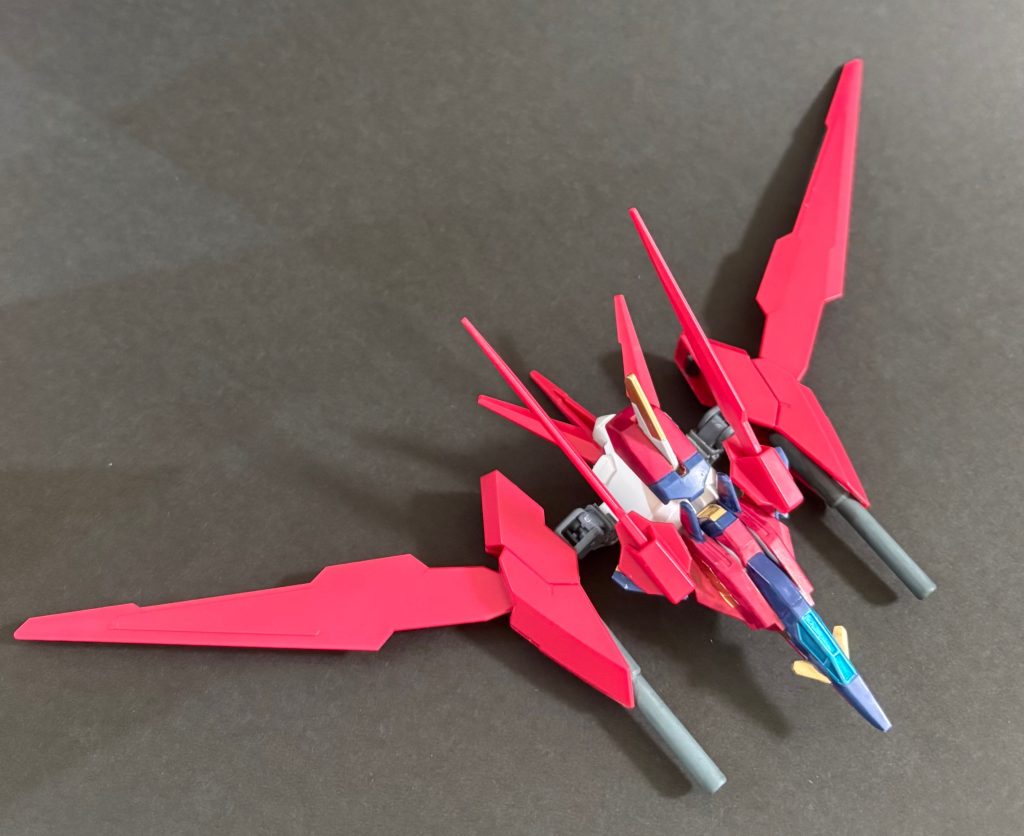 機体概要C.E.75。マイティーストライクフリーダムの圧倒的な戦闘能力は、余りに強大であり、その存在を危険視する声も上がっていた。その危険性を最も理解していたのは、他ならぬキラ・ヤマト自身である。精神干渉によって暴走した経験を持つ彼は、自らが常に正しい判断を下せる保証はないことを認識していた。もし自分やラクス・クラインが誤った道を選んだならば。もしマイティーストライクフリーダムの力が制御不能となったならば。その時、自分たちを止める存在が必要である。キラはその役目をアスラン・ザラに託すことを決意し、対マイティーストライクフリーダム戦を想定した専用機の開発を提案した。こうして始動したのが、後に「Project DIVINITY」と呼ばれる極秘開発計画である。&nbsp;相転移エンジン『ディバイン・コア』&nbsp;本機に搭載された核を用いない大出力の動力機関。DSSDが開発した局所真空相転移炉「レアクトゥール・ソレール」をMSエンジンに技術転用したもの。炉内で生じるVP粒子を抽出することで莫大なエネルギーを獲得する。また、VP粒子自体の特性を利用して、機体や武装に様々な機能を付与している。&nbsp;コア・ブースターファトゥムやフォランティスの流れを汲む自立支援戦闘機。合体する事で、機体のVP粒子制御能力を飛躍的に向上させ、VPSFオーバーロードを発動可能となる。&nbsp;最強の矛に対する、無敵の盾「VPSFオーバーロード」発動状態にフェーズシフトしたイモータルジャスティス・ディヴィニティは、高密度位相安定領域を実体剣の刀身周囲に集中展開し、ディスラプターを斬撃によって無効化する事が可能となる。尚、対ディスラプター戦術の実行にはアスランの卓越した戦闘技能が必要不可欠である。