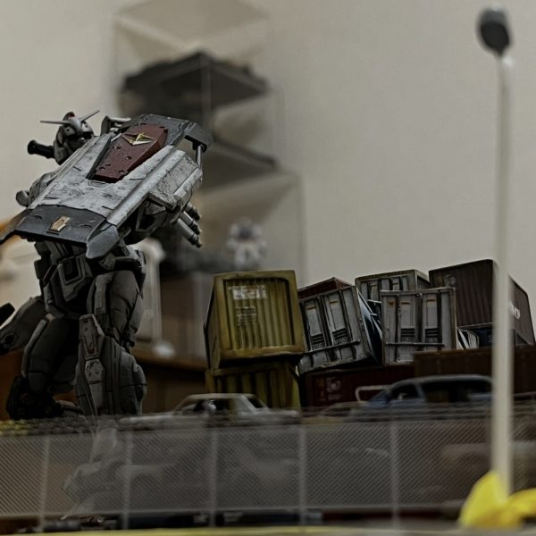 街灯とフェンス越しのガンダム。好きなアングルです。街灯は自作です。フェンスは高価なエッジングパーツ😅。レイアウトを確認中です。黄色のコンテナの上に緑のコンテナを追加しますが吹っ飛んでガンダムのシールドにぶち当たってる感じが良いかなと思ってます。ジャンクパーツや廃材をそこら中に散らかしたいのですが考えて作るの難しいですね😓もう少しなんですけどね…😅（2枚目）