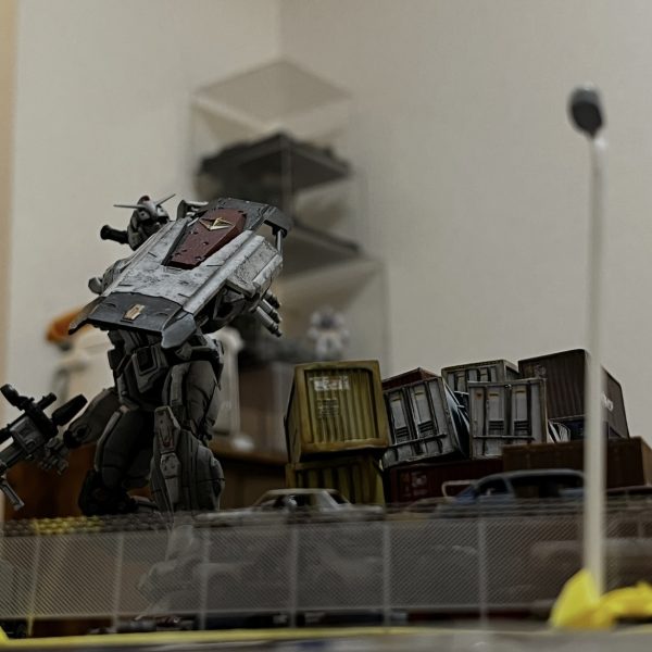 街灯とフェンス越しのガンダム。好きなアングルです。街灯は自作です。フェンスは高価なエッジングパーツ😅。レイアウトを確認中です。黄色のコンテナの上に緑のコンテナを追加しますが吹っ飛んでガンダムのシールドにぶち当たってる感じが良いかなと思ってます。ジャンクパーツや廃材をそこら中に散らかしたいのですが考えて作るの難しいですね😓もう少しなんですけどね…😅（3枚目）