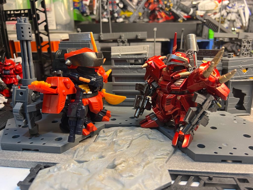 ザッパーザク：「フハハハ！ ここにガンダムをボコボコに叩きのめしたっていう『伝説のザク大総帥』がいるって聞いたぜ？ このオレ様——ダークディメンションの狂暴なる撃滅者ザッパーザク様が、直々に教えを請いに来てやったのさ……」（ブラッディザクは冷ややかな視線で振り向く。背背の巨大なガトリングガンと肩のノコギリ甲冑が影の中で重々しい金属の威圧感を放ち、モノアイが不気味な赤い光を宿す）ブラッディザク：「……うるせえガキだ。ガンダムの塗装すら傷つけられねえそのおもちゃは、清掃用のほうきか何かか？」ザッパーザク：（その圧倒的な気圧され、思わず後ずさりして唾を飲み込む。慌ててペコペコと腰を低くし、態度を一変させる）「へ、へい……ブラッディザクの兄貴！ 無礼をお許しくだせえ！ 自分、兄貴がかつて大陸進攻戦でコマンドガンダムを単機で叩きのめしたって聞きやして……『ガンダムを徹底的に粉砕する』秘密の裏技を教わりに来たんでさあ！」