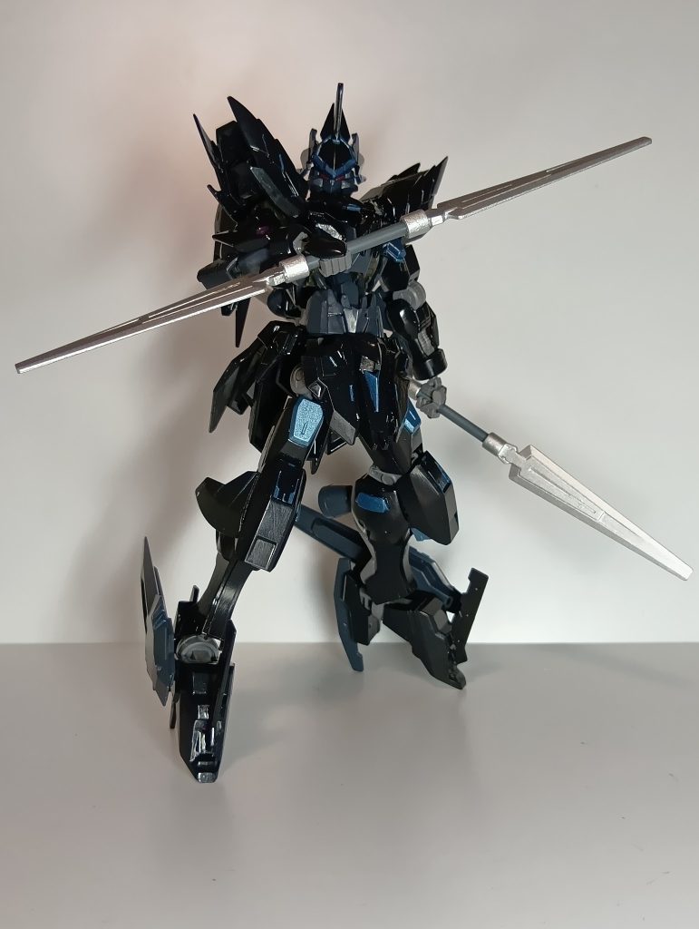 ○魔装兵ズィリオスⅡ(ツヴァイ)[解説]暗黒騎士リコス・ユミアの専用機としてレギンレイヴを改修した第七世代魔装兵。以前に搭乗していたノクス・ズィリオスが中破したことにより、ベース機体をレギンレイヴに変更して新規設計された。中破したノクス・ズィリオスは半騎馬形態への変形時の隙を狙われた事でダメージを負っている為、ズィリオスⅡでは半騎馬形態への変形をオミットし、人型でも同等の高機動性を発揮するように内蔵式グライデンパックのレイアウトを変更している。さらに手持ち武装はダブルファングを大型化したダブルファングⅡのみとした。これはリコスが双翼刃の扱いに習熟した事で、他の武装を混じえるとかえって効率が悪くなった為である。また、脚部の爪先と踵にイシルディン製ブレードを固定装備し、高機動から相手の意表を突く必殺の蹴りを見舞う事が出来る。&nbsp;聖華歴839年、傷を癒し新たなる牙を手に入れた黒き狼は、自らの仲間を護る為に戦場を縦横無尽に駆け巡り、血風を巻き起こす。