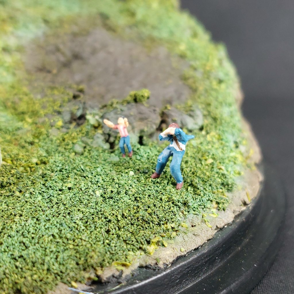■フィギュア(その2/2)　アムロは、ビルダーズパーツのポーズ変えで、ギュネイと同型のフィギュアを加工して製作しました。ホビー・ハイザックのスラスター噴射に耐えているような大胆なポーズにしています。ジャケットが強風で煽られるさまは、極小のプラペーパーと瞬間接着パテで再現しました。強風に晒されているネクタイは、シャアと同じく塗装で表現しました。　クェスとハサウェイは、パッと見で子どもであることが判別できるよう、シャアやアムロとの体格差を演出することにし、５頭身くらいで製作しました。2体ともKATOのNゲージのフィギュアから改造しています。当初、ハサウェイは地面に四つん這いになって強風を耐えている姿で固定するつもりでしたが、よりドラマチックに見えるよう、両手を挙げたポーズに変更しました。シャアについて行ってしまうクェスの身を案じる心情を表現できたと思います。