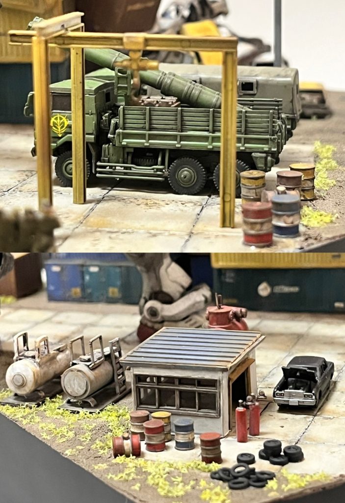 ピットロードの1/144自衛隊3.5tトラックにジオンのデカール。荷台にはマゼラトップの砲身2本を積み込みました。劇中でもトラックに砲身を積み込むシーンが出てきます。作業小屋の隣にある２つのタンクも劇中に風景として出てきます（サイズは小さいですが😅）。