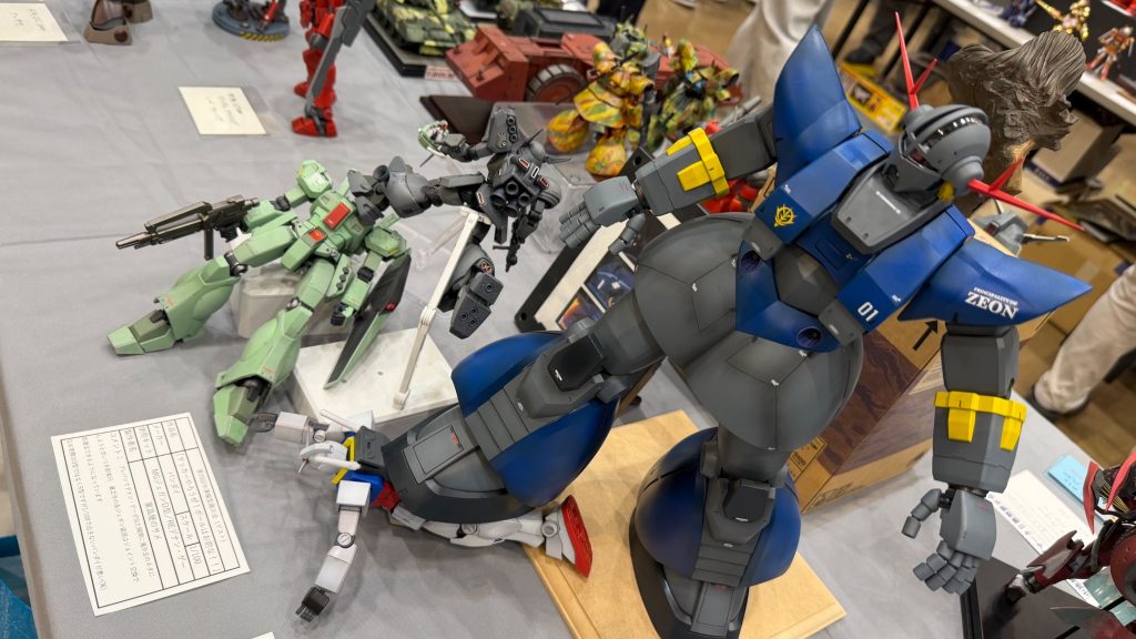フロントスカートの都合上脚が上がらない為木製の展示台を使ってガンダムを踏む高さを稼いでいます　なお隣に写っているのは過去作「サッカーやろうぜボールはお前な！」の２機です