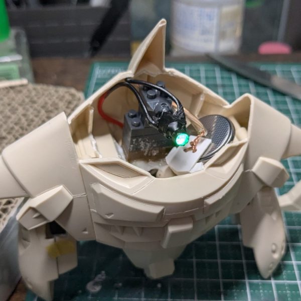 数日試行錯誤しながらLED発光モノアイユニットを本体に設置する工作とかしてみたりしてました。最初に作ったモノアイはあれこれしてたらLEDの根本のラインがぽきっと折れてお亡くなりになりました。縦横2軸の可動アームとかつくったのに。。。私の心も折れたので、結局いつものとおりDAISOプチブロックさんのボールジョイントを頼りにする方向に逃げました。電源のON/OFFは自作適当ボックスへの電池の抜き差しという割り切った仕様。スイッチ付きの電池ボックスも買ったんですがちょいとサイズが大きくておさまらなかった。グーンさんの大きな身体のおかげもあって電池含めてぜんぶ内側におさまるようになりました。工作は雑ですが。まあこれでも通常モードと巡行モードのモノアイ位置移動ができるので良いことにします。問題ナシ。あと基部にブロックを使ったのでモノアイユニットが脱着できるのはメンテナンス考えると良かったかもしれない。次は足裏の肉抜き埋めとか形状修正とかかなあ。(1枚目)